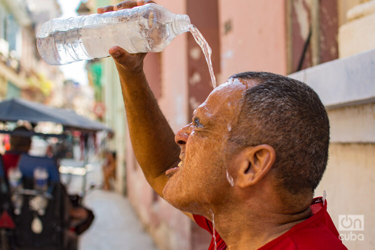 Un hombre se echa agua para refrescar del intenso calor del verano. Foto: Otmaro Rodríguez.