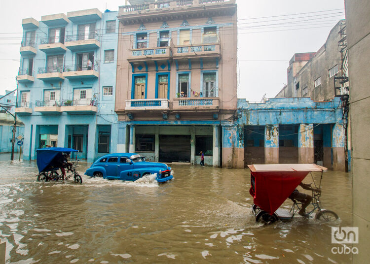 Un auto y dos bicitaxis transitan por la zona de Cuatro Caminos, en La Habana, sitio inundado por las lluvias de la tormenta Debby, el 4 de agosto de 2024. Foto: Otmaro Rodríguez.