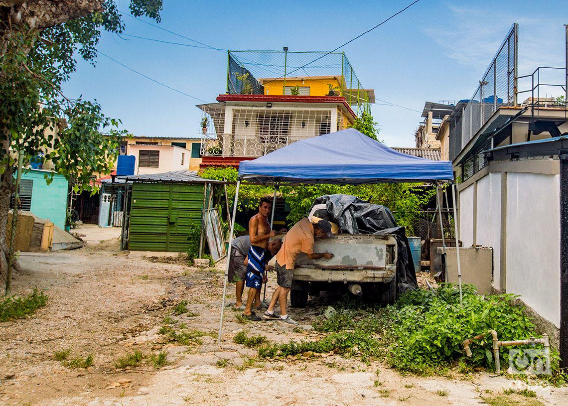 Hombres reparando un auto en el barrio habanero de La Timba. Foto: Otmaro Rodríguez.