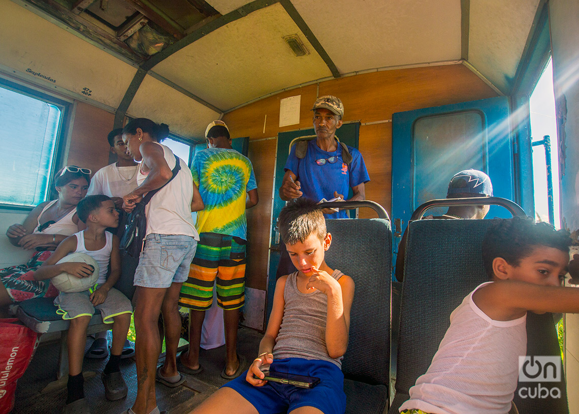 El cobrador de pasajes junto a pasajeros del tren a las playas del este de La Habana. Foto: Otmaro Rodríguez.