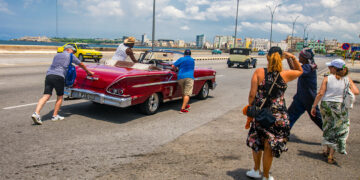 Turistas ayudan a empujar un auto clásico en La Habana. Foto: Otmaro Rodríguez.