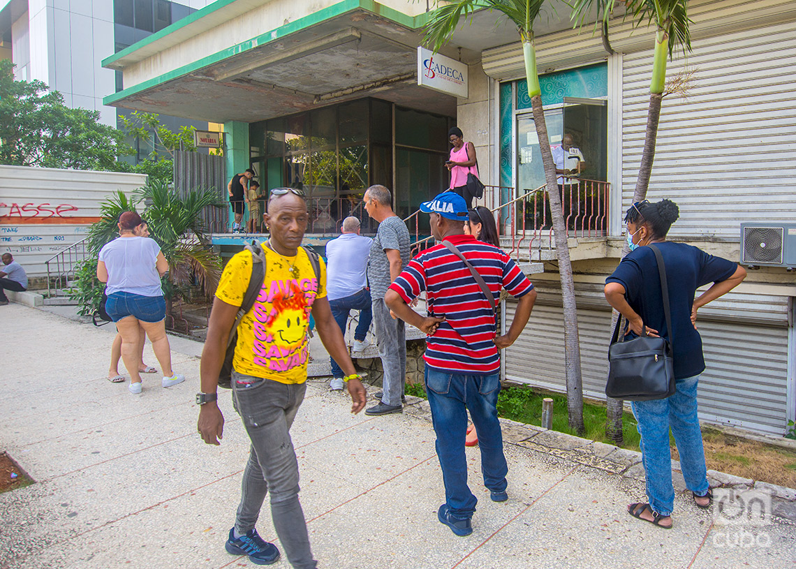 Personas caminan y hacen cola en una Cadeca en el Vedado. Foto: Otmaro Rodríguez.