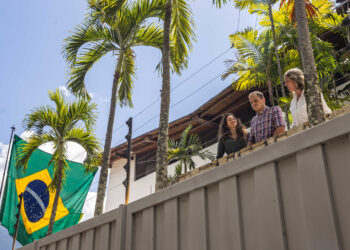 Claudia Macero (i), Pedro Uchurrurtu (c) y Magalli Meda, asilados en la residencia del embajador de Argentina, saludan desde un balcón con la bandera de Brasil a un costado. Foto: Henry Chirinos/EFE.