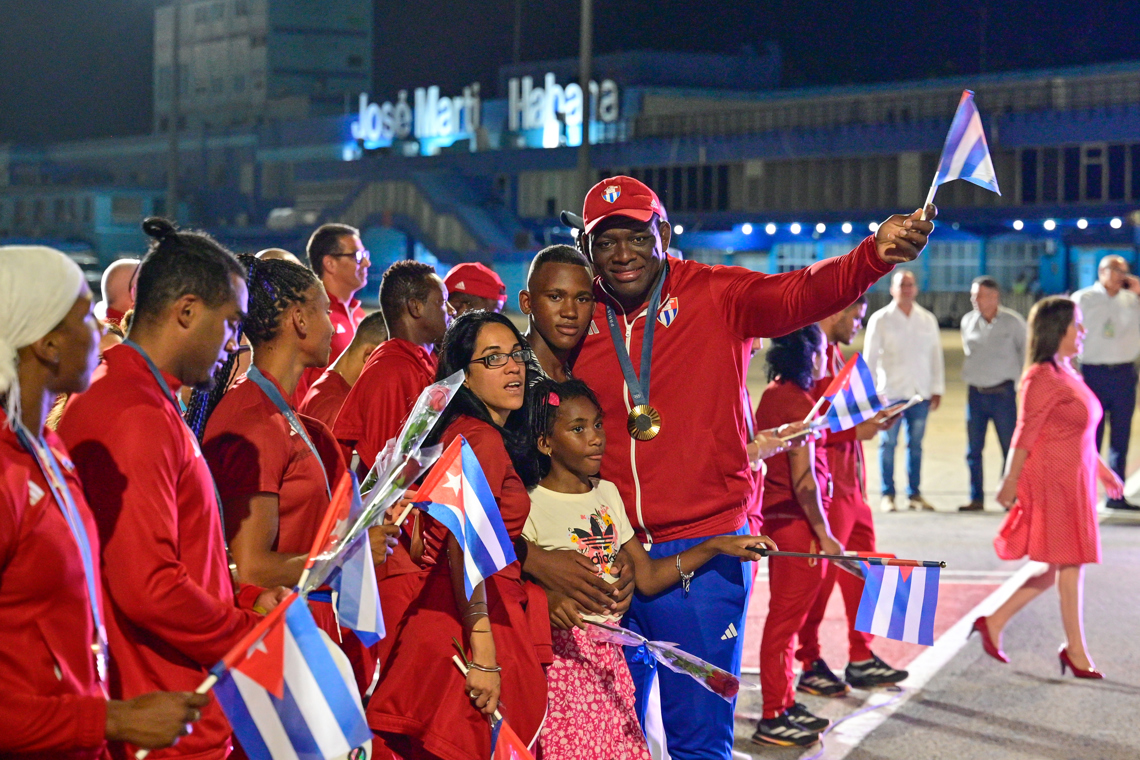 El luchador cubano Mijaín López, cinco veces campeón olímpico, posa con sus hijos a su llegada al aeropuerto José Martí de La Habana,  luego de participar en los Juegos Olímpicos de París 2024. Foto: Adalberto Roque / POOL / AFP vía EFE.