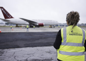 Trabajadora de migración observa el avión que transporta a los 135 nicaragüenses liberados este jueves, en el Aeropuerto Internacional La Aurora, en la Ciudad de Guatemala. Foto: Gobierno De Guatemala/EFE.