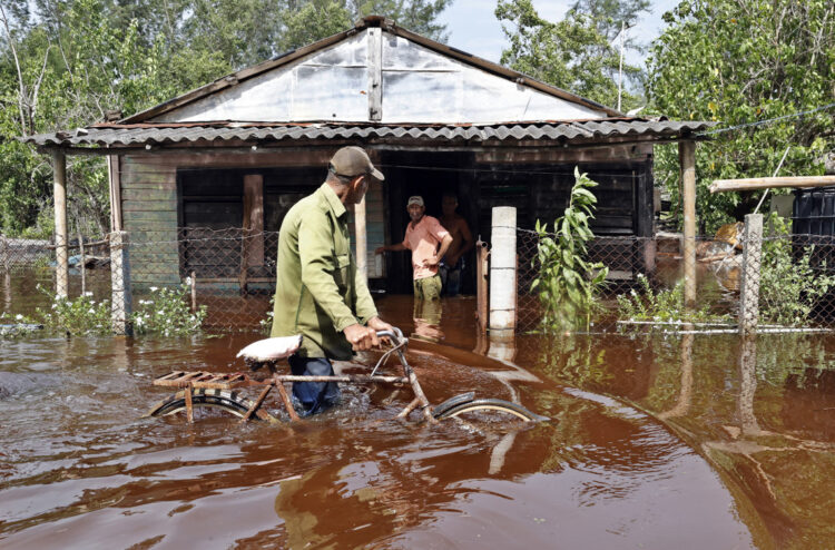 Un hombre camina con una bicicleta por una calle inundada de agua del mar tras el paso del huracán Helene, en el poblado de Guanímar, en la costa sur de la provincia cubana de Artemisa. Foto: Ernesto Mastrascusa / EFE.