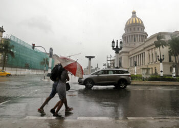 Personas bajo la lluvia en La Habana. Foto: Ernesto Mastrascusa / EFE / Archivo.