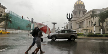 Personas bajo la lluvia en La Habana. Foto: Ernesto Mastrascusa / EFE / Archivo.