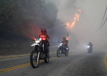 Policías patrullan en moto, cerca de un incendio forestal, en Guapulo. Foto:  Santiago Fernández/EFE.