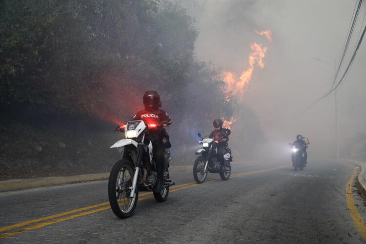 Policías patrullan en moto, cerca de un incendio forestal, en Guapulo. Foto:  Santiago Fernández/EFE.