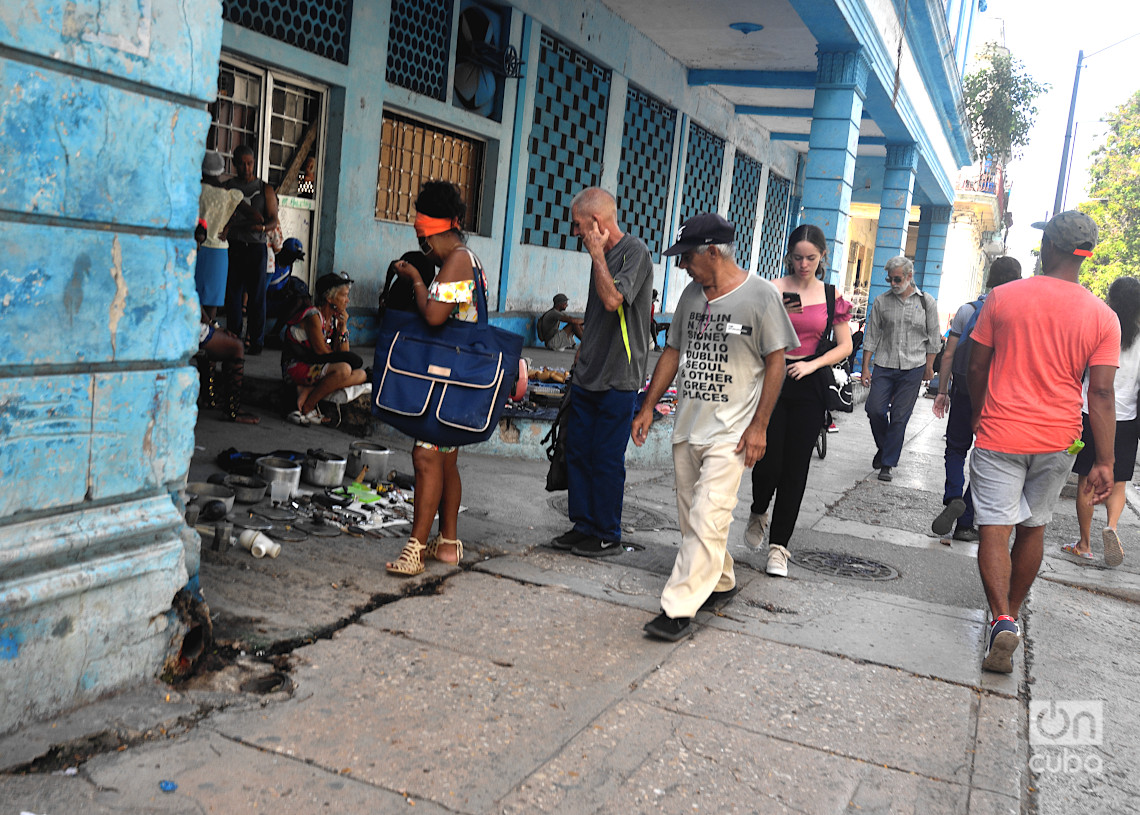 Personas pasan y observan los productos a la venta en un puesto callejero en La Habana. Foto: Otmaro Rodríguez.