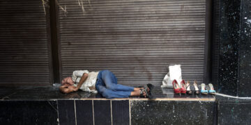 Una persona duerme en las afuera del banco metropolitano de la calle Empedrado, junto a zapatos que tiene en venta. Foto: Otmaro Rodríguez.