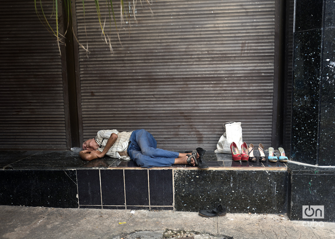 Una persona duerme en las afuera del banco metropolitano de la calle Empedrado, junto a zapatos que tiene en venta. Foto: Otmaro Rodríguez.