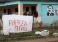 Varios hombres conversan en el exterior de una vivienda en la región de San Antonio del Sur una semana después del paso de la tormenta tropical Oscar. Foto: Ernesto Mastrascusa / POOL / EFE.