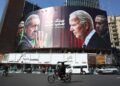 Iraníes pasan por un edificio decorado con un cartel contra Israel con las imágenes del presidente, Masoud Pezeshkian, y comandante general de la Guardia Revolucionaria, Mohammad Bagheri (i), el presidente de EEUU, Joe Biden, y el de Israel, Benjamin Netanyahu, en la plaza de Valiasr en Teherán. Foto: Abedin Taherkenareh / EFE.