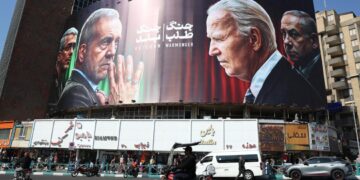 Iraníes pasan por un edificio decorado con un cartel contra Israel con las imágenes del presidente, Masoud Pezeshkian, y comandante general de la Guardia Revolucionaria, Mohammad Bagheri (i), el presidente de EEUU, Joe Biden, y el de Israel, Benjamin Netanyahu, en la plaza de Valiasr en Teherán. Foto: Abedin Taherkenareh / EFE.