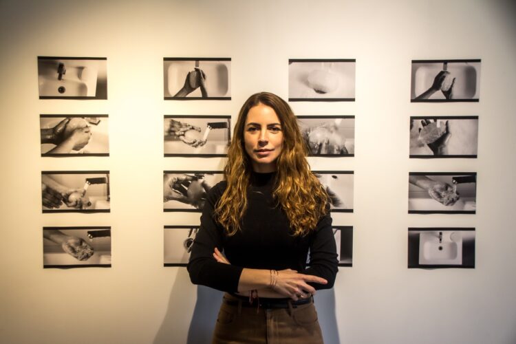 Laura Lis junto a imágenes del videoarte "Brainwashing" (2024). Foto: Cortesía de la entrevistada.