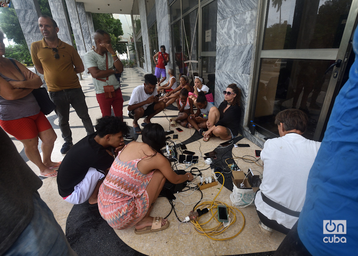 Personas cargan sus teléfonos móviles en La Habana un día después del azote del huracán Rafael. Foto: Otmaro Rodríguez.