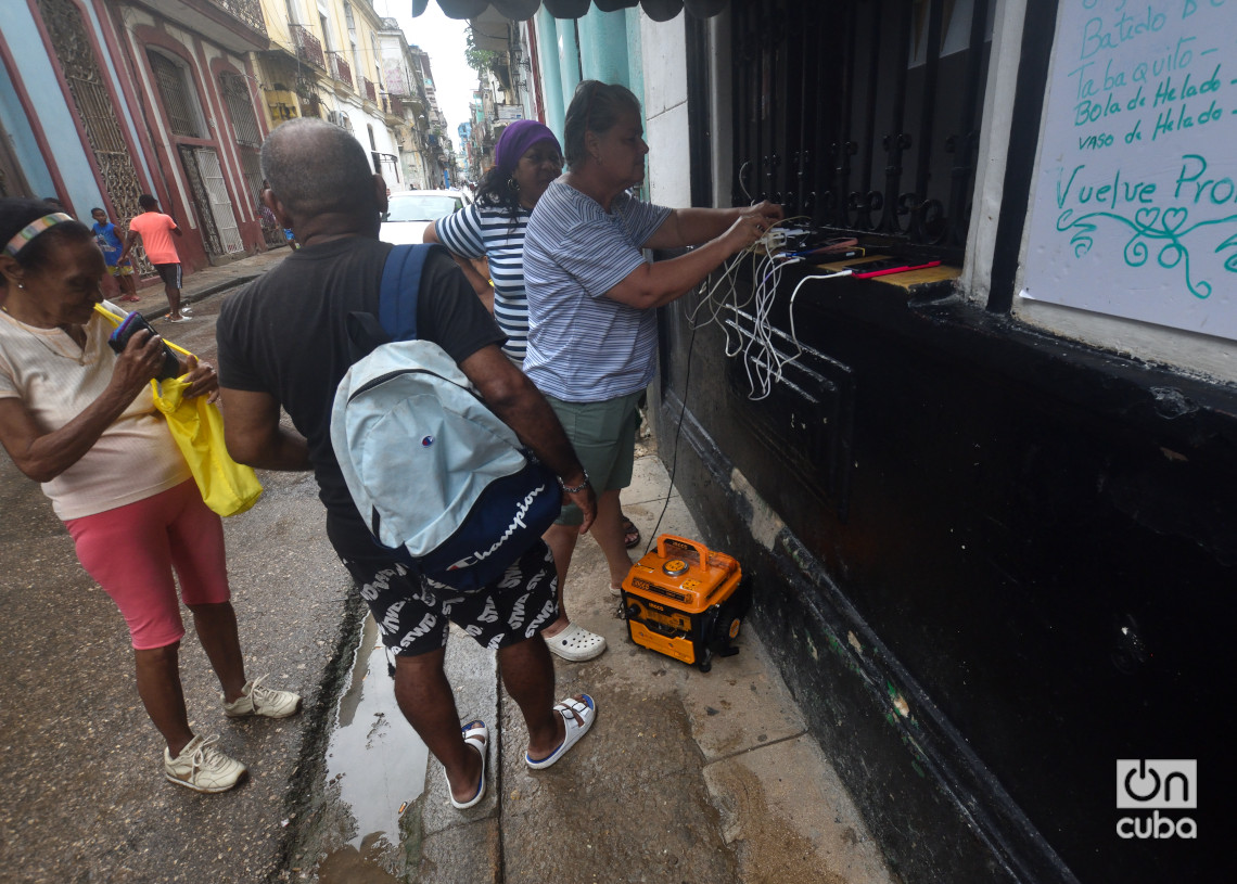 Personas cargan sus teléfonos móviles en La Habana un día después del azote del huracán Rafael. Foto: Otmaro Rodríguez.