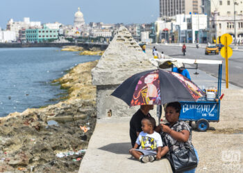 Una familia cubana bajo una sombrilla en el malecón, La Habana. Foto: Kaloian Santos Cabrera.