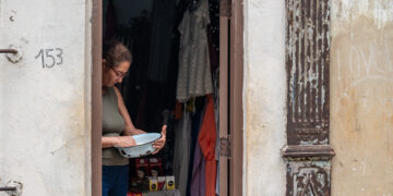 Una mujer limpia un arroz para cocinar, junto a un puesto de venta particular, a la entrada de su casa. Foto: Kaloian / Archivo.