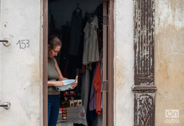 Una mujer limpia un arroz para cocinar, junto a un puesto de venta particular, a la entrada de su casa. Foto: Kaloian / Archivo.