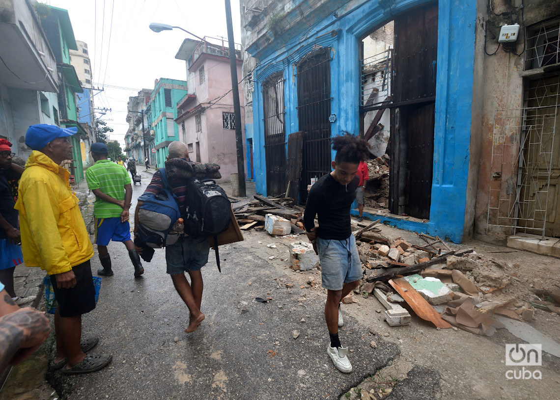 Personas pasan frente a un derrumbe en la calle Santiago, La Habana, como consecuencia del azote del huracán Rafael. Foto: Otmaro Rodríguez.