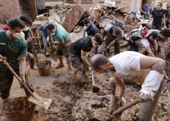 Varias personas retiran el lodo acumulado en una calle de la localidad valenciana de Paiporta, Foto: Biel Alino/EFE.