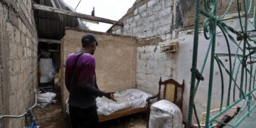 Un hombre observa los daños causados en su vivienda por el huracán Rafael, en Artemisa. Foto: Ernesto Mastrascusa / EFE.