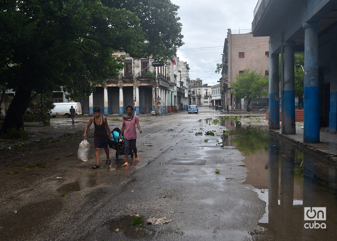 Personas caminan con sus pertenecías por la calle Monte, en La Habana, un día después del azote del huracán Rafael. Foto: Otmaro Rodríguez.