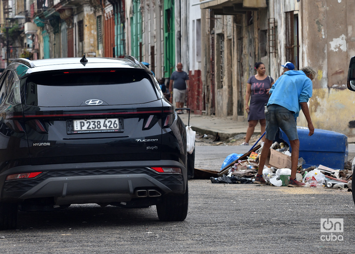 Un auto transita cerca de un hombre que hurga en la basura en La Habana, un día después del azote del huracán Rafael. Foto: Otmaro Rodríguez.