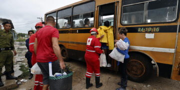 Integrantes de la Cruz Roja cubana ayudan a unas personas a subir a un autobús durante una evacuación en el Surgidero de Batabanó antes de la llegada del huracán Rafael a Cuba, en noviembre de 2024. Foto: Ernesto Mastrascusa / EFE / Archivo.