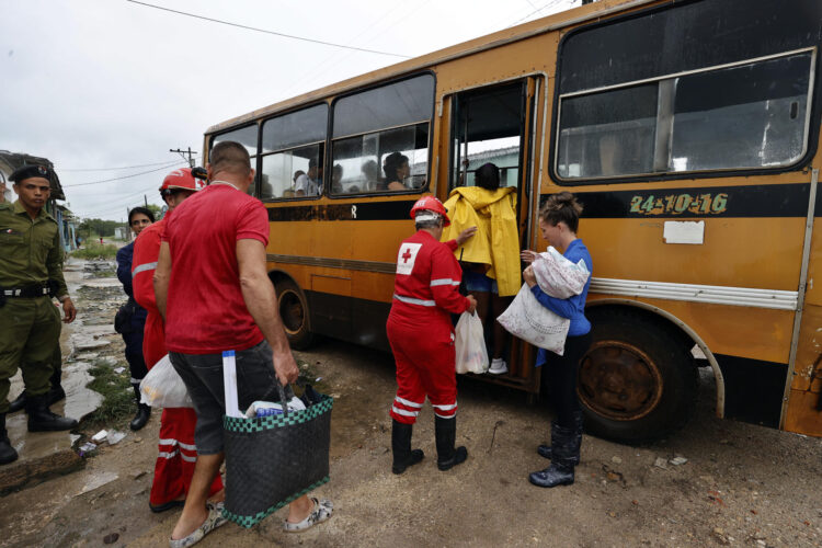Integrantes de la Cruz Roja cubana ayudan a unas personas a subir a un autobús durante una evacuación en el Surgidero de Batabanó antes de la llegada del huracán Rafael a Cuba, en noviembre de 2024. Foto: Ernesto Mastrascusa / EFE / Archivo.