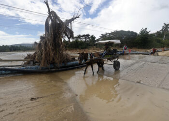 Un hombre transita por una calle inundada en la región de San Antonio del Sur tras el paso de la tormenta tropical Óscar, en Guantánamo. Foto: Ernesto Mastrascusa/ POOL/EFE.