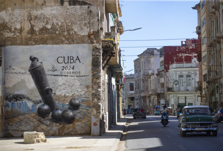 Un carro pasa frente a un grafiti en la calle San Lázaro, en La Habana (Cuba). Foto: EFE/Yander Zamora.