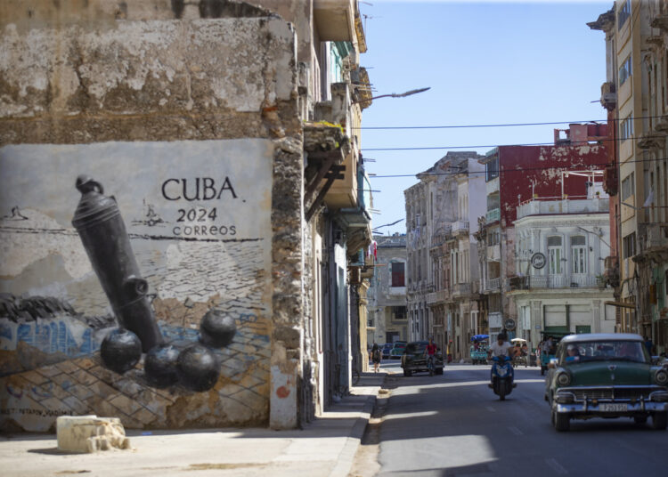 Un carro pasa frente a un grafiti en la calle San Lázaro, en La Habana (Cuba). Foto: EFE/Yander Zamora.