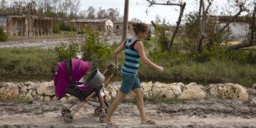 Una mujer arrastra un coche de bebé por una de las calles de playa Guanimar, uno de los sitios afectados por el paso del huracán Rafael, el 20 de noviembre de 2024 en Artemisa. Foto: Yander Zamora / EFE.