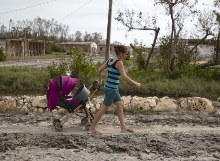 Una mujer arrastra un coche de bebé por una de las calles de playa Guanimar, uno de los sitios afectados por el paso del huracán Rafael, el 20 de noviembre de 2024 en Artemisa. Foto: Yander Zamora / EFE.