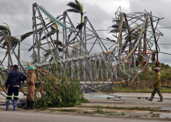 Trabajadores junto a una torre de energía caída tras el paso del huracán Rafael. Foto: Ernesto Mastrascusa/EFE.