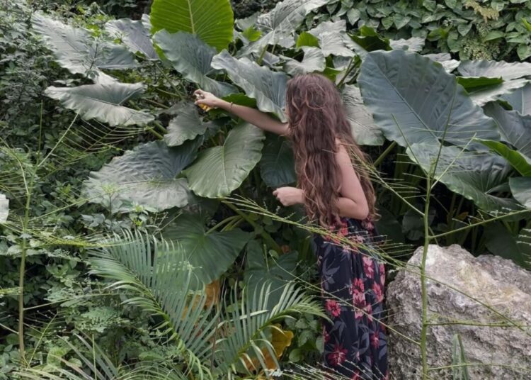 Una chica esparce perfume entre las plantas al fondo de un callejón para conformar la obra “Bosque con Chanel no.5” (2016).