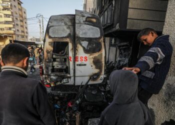 Ciudadanos palestinos frente a un vehículo destruido cerca del hospital Al Awda por un bombardeo de las fuerzas israelíes. Foto: Mohammed Saber /EFE.