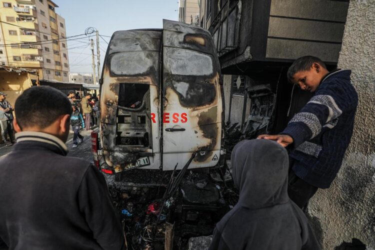 Ciudadanos palestinos frente a un vehículo destruido cerca del hospital Al Awda por un bombardeo de las fuerzas israelíes. Foto: Mohammed Saber /EFE.