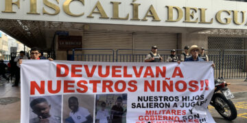 Dos personas sostienen un cartel en los exteriores de la Fiscalía Provincial del Guayas con el mensaje "devuelvan a nuestros niños", en alusión a los cuatro menores desaparecidos el 8 de diciembre en Guayaquil, Ecuador. Foto: Cristina Bazán / EFE.