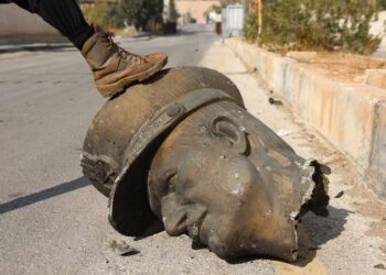 Un combatiente de la oposición pisa la estatua decapitada del fallecido presidente sirio Hafez Al Asad (padre de Bashar Al Asad) en el aeropuerto militar de Mezzeh en Damasco. Foto: EFE/EPA/MOHAMMED AL RIFAI.