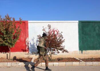 Khan Sheikhoun, 03/12/2024.- Un miembro de la oposición siria camina delante de un muro pintado con los colores de la bandera iraní en una posición militar supuestamente utilizada por las fuerzas iraníes después de que fuera capturada por la oposición siria en la ciudad de Khan Sheikhoun, en la campiña de Idlib, Siria, 03 Diciembre de 2024. Las fuerzas de oposición sirias, lideradas por el grupo militante islamista Hayat Tahrir al-Sham (HTS), lanzaron una ofensiva el 27 de noviembre, tomando gran parte de Alepo, Siria. segunda ciudad más grande. La ofensiva desencadenó contraataques de las fuerzas del régimen sirio, así como ataques aéreos rusos y sirios contra zonas controladas por la oposición. (Rusia, Siria) Foto: EFE/EPA/MOHAMMED AL RIFAI