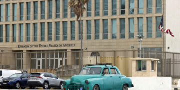 Un auto clásico de fabricación norteamericana, pasa frente a la embajada de Estados Unidos en La Habana. Foto: Ernesto Mastrascusa / EFE.