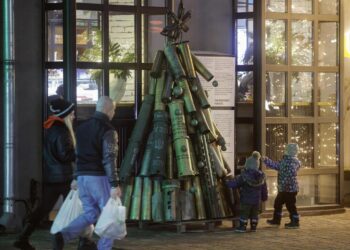 La gente pasa junto a un árbol de Navidad hecho con munición usada e instalado cerca de una cafetería en la víspera de Año Nuevo en el centro de Kiev, Ucrania, el 31 de diciembre de 2024. Foto: EFE/EPA/SERGEY DOLZHENKO.