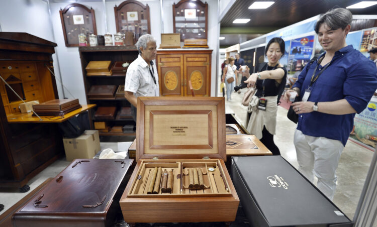 Personas asisten a la feria comercial del XXV Festival del Habano, este lunes en el Palacio de Convenciones. Foto: Ernesto Mastrascusa/EFE.