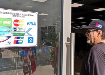 Un hombre observa el cartel con las tarjetas magnéticas que pueden usarse para realizar compras en el nuevo el Supermercado de 3ra y 70, en La Habana. Foto: Ernesto Mastrascusa / EFE.