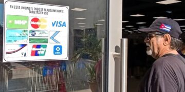 Un hombre observa el cartel con las tarjetas magnéticas que pueden usarse para realizar compras en el nuevo el Supermercado de 3ra y 70, en La Habana. Foto: Ernesto Mastrascusa / EFE.